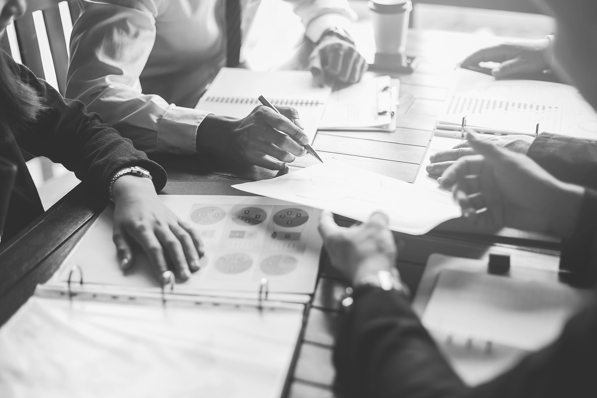 여러 사람이 테이블에 모여 서류를 검토하며 회의하는 흑백 사진